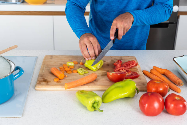 Close up hands of young sporty man cutting and cooking fresh natural vegetables at kitchen and cooking for healthy lunch. Self care yoga nutritionist male having healthy meal after workout. - Foto, Bild