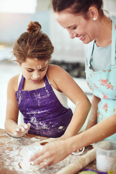 Cooking up something yummy. a mother and daughter preparing food in the kitchen at home - Фото, изображение