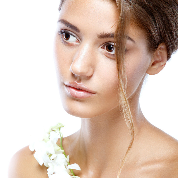 Young woman with clear face natural make up her hair up with a white flower on a light background - Fotoğraf, Görsel