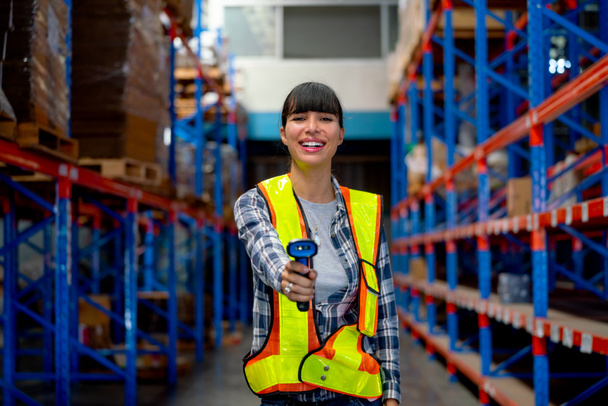 Portrait of Cacuasian warehouse worker hold barcode scaner and point at camera stay on way between shelves in workplace. Concept of professional factory worker support for delivery system. - Foto, afbeelding