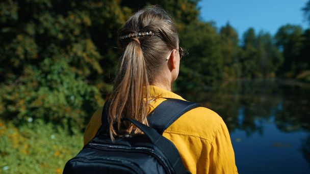 Woman tourist with backpack standing near the lake. - Фото, изображение