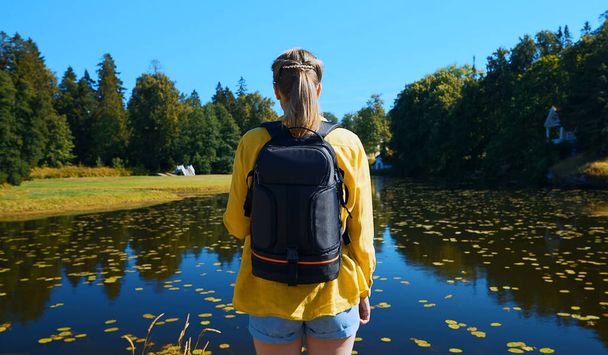 Woman tourist with backpack standing near the lake. - Foto, afbeelding