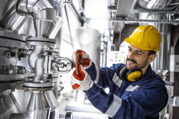 Refinery factory worker closing valve on gas pipeline in petrochemical industrial plant. - Fotoğraf, Görsel