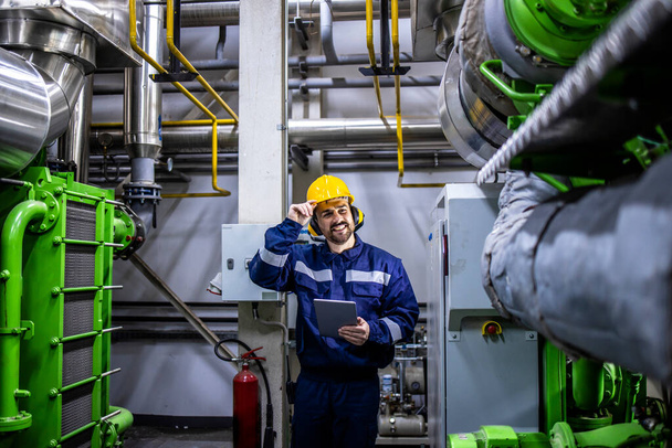 Caucasian industrial serviceman checking gas generators for electricity in heating plant. - Fotó, kép