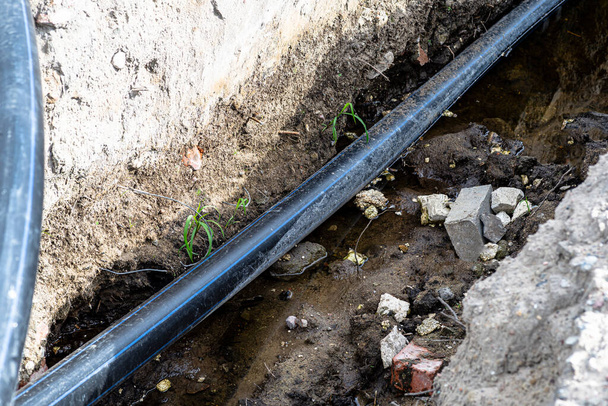 Plastic water pipe lying in a ditch with high groundwater, water connection on the estate. - Foto, Bild