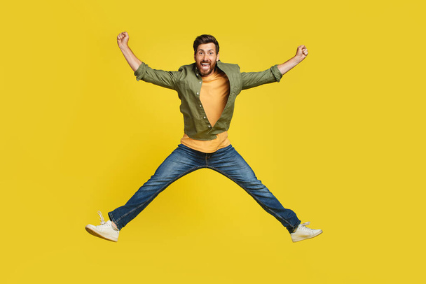 Expressing happiness. Full length studio shot of excited middle aged man jumping over yellow background. Happy male celebrating success or victory, copy space - Photo, image
