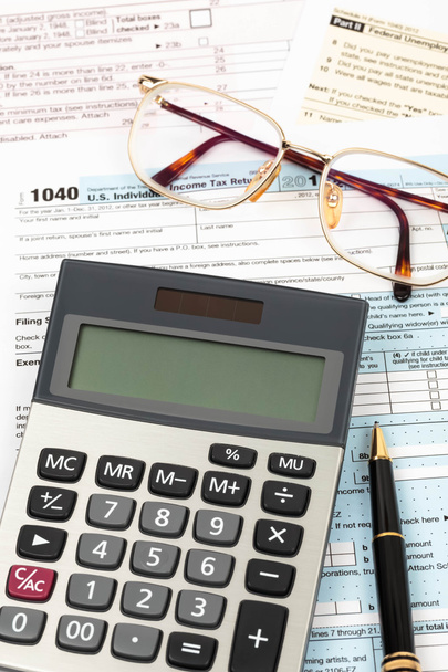 Formulario de impuestos con pluma, calculadora, y el concepto de impuestos gafas
 - Foto, imagen