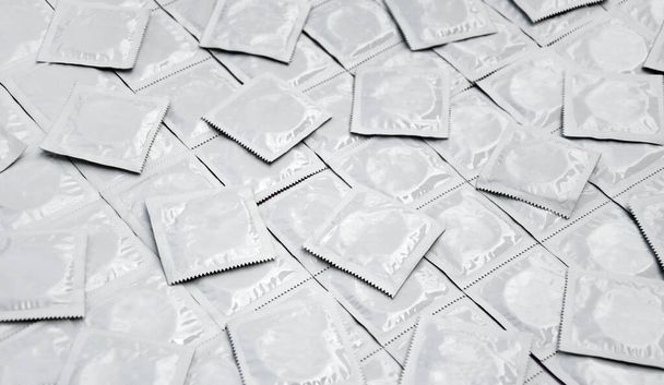 Many white packages of unopened condoms as a background. Using a condom to reduce the chance of pregnancy or sexually transmitted diseases, STDs. The concept of safe sex and reproductive health. - Zdjęcie, obraz