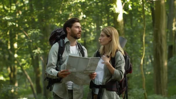 Τουρισμός και πλοήγηση πρόβλημα. Συναισθηματικός άνδρας και γυναίκα τουρίστες που χάνονται κατά τη διάρκεια του ταξιδιού στο δάσος, υποστηρίζοντας με το χάρτη, αίσθημα διαφωνούν για τη διαδρομή και πηγαίνει σε διαφορετικές κατευθύνσεις, αργή κίνηση - Πλάνα, βίντεο