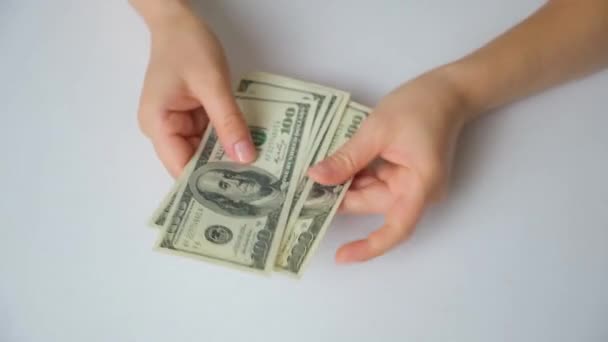 A woman counts dollar bills for 100 dollars on a white background, top view. - Filmagem, Vídeo