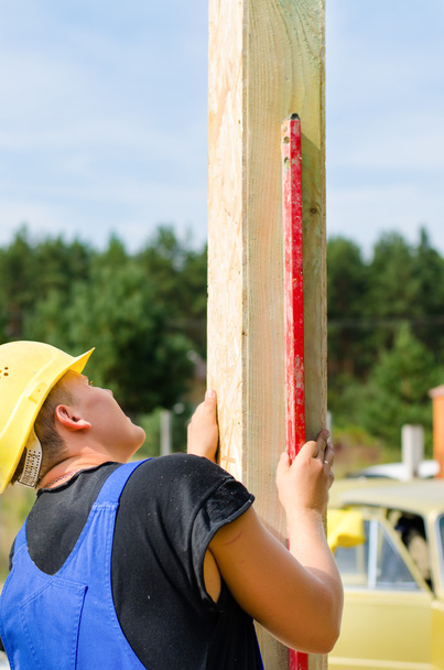 Builder ensuring that a beam is vertical - Photo, Image