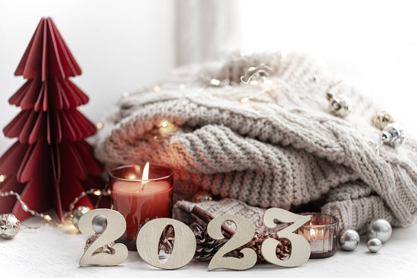 Cozy winter composition with wooden numbers 2023, candles and a knitted element. - Foto, imagen