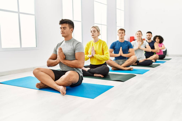 Group of young people concentrated training yoga at sport center. - Foto, afbeelding