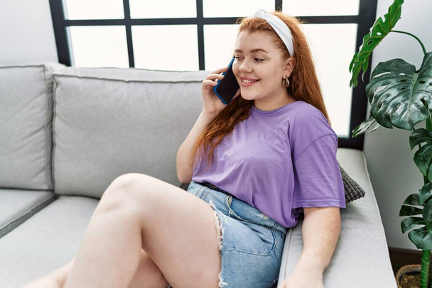 Young redhead woman smiling confident talking on the smartphone at home - Photo, image