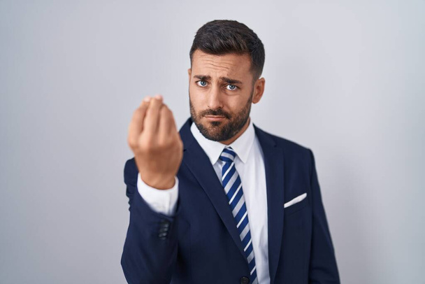 Handsome hispanic man wearing suit and tie doing italian gesture with hand and fingers confident expression  - Fotó, kép