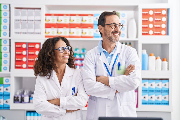 Чоловік і жінка фармацевти посміхаються впевнено стоячи на руках схрестили жест в аптеці
 - Фото, зображення