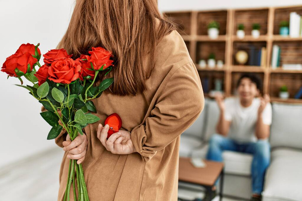 Woman suprising man with bouquet of roses at home. - Foto, imagen