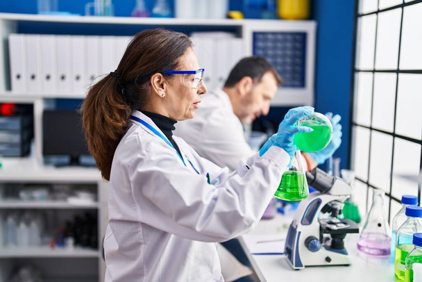 Μεσήλικες επιστήμονες που μετρούν υγρά στο εργαστήριο - Φωτογραφία, εικόνα