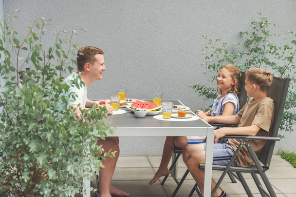 Happy dad with teen children having brunch outdoors in private garden - Photo, Image