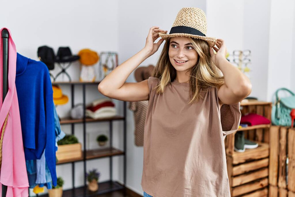 Young caucasian woman wearing hat shopping at clothing store - Φωτογραφία, εικόνα