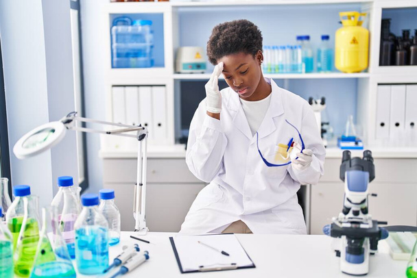 African american woman wearing scientist uniform stressed working at laboratory - 写真・画像