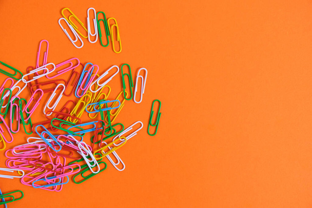 Colored paper clips on a orange background - Foto, afbeelding