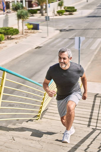 Hombre hispano de mediana edad usando ropa deportiva corriendo por la calle - Foto, Imagen