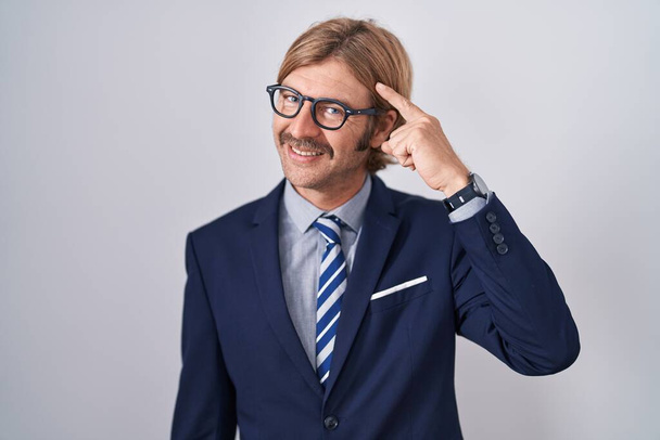 Caucasian man with mustache wearing business clothes smiling pointing to head with one finger, great idea or thought, good memory  - Photo, Image