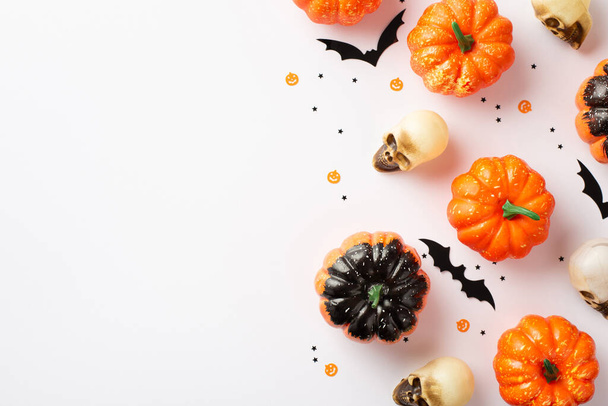 Halloween creepy decorations concept. Top view photo of pumpkins skulls bat silhouettes and confetti on isolated white background with copyspace - Zdjęcie, obraz