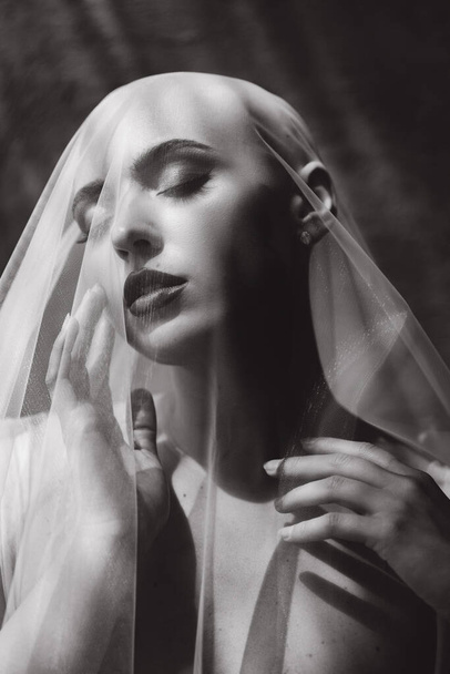Bald beautiful bride in a luxurious wedding dress in red lipstick and a long veil is sick with cancer - Foto, Imagen