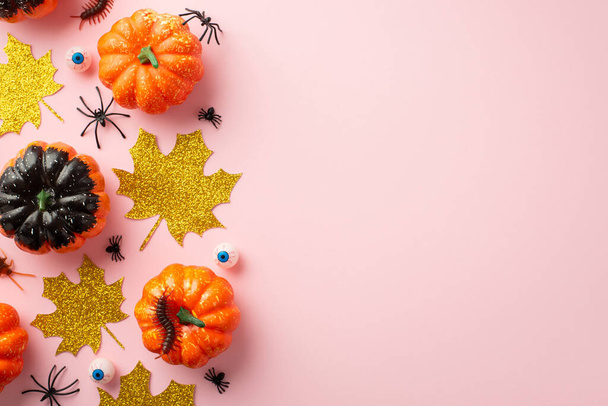 Halloween decorations concept. Top view photo of pumpkins gold glitter leaves spooky eyes insects spiders and centipede on isolated pastel pink background with copyspace - 写真・画像