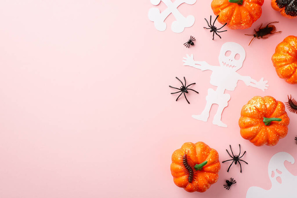 Halloween scary decorations concept. Top view photo of ghost skeleton bones silhouettes pumpkins spiders cockroach and centipedes on isolated pastel pink background with copyspace - Zdjęcie, obraz