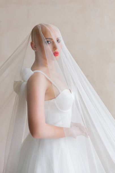Bald beautiful bride in a luxurious wedding dress in red lipstick and a long veil is sick with cancer - Foto, Bild