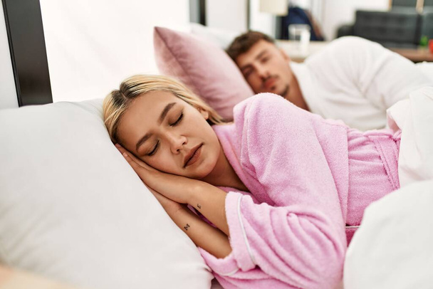 Jeune couple caucasien dormant allongé sur le lit à la maison. - Photo, image