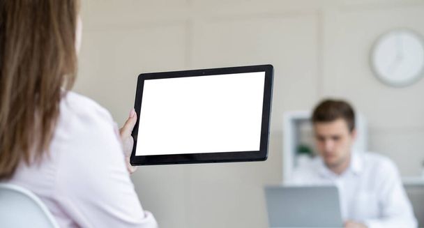 Digital technology. Office work. Computer mockup. Unrecognizable woman holding tablet computer blank screen with male colleague in light room interior. - Фото, изображение