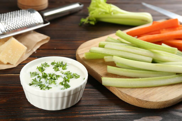 Celery and carrot sticks with dip sauce on wooden table, closeup - Fotoğraf, Görsel