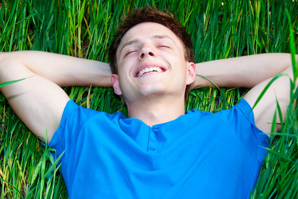 緑の草に横たわっている男 - 写真・画像