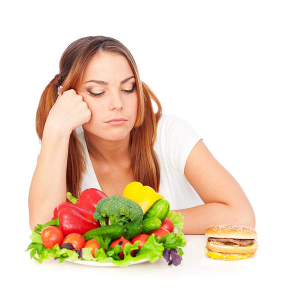 Sad woman choosing burger or vegetables - 写真・画像