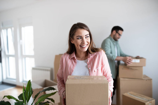 Couple moving in in their new apartment carrying cardboard boxes - Foto, Imagem