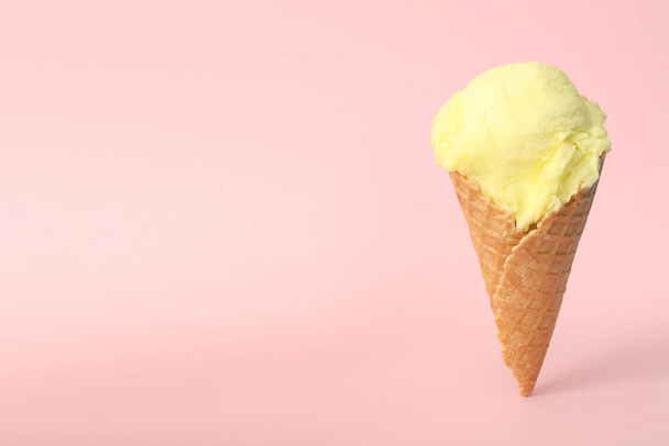 Delicious yellow ice cream in waffle cone on pink background. Space for text - Foto, Imagem