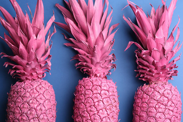 Pink pineapples on blue background, flat lay. Creative concept - Foto, Imagen