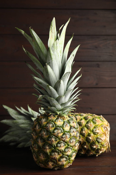 Fresh ripe juicy pineapples on wooden table - Fotoğraf, Görsel