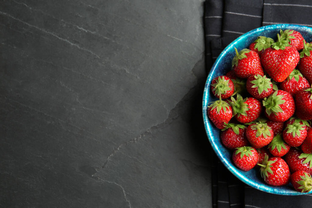 Delicious ripe strawberries in bowl on black table, flat lay. Space for text - Φωτογραφία, εικόνα