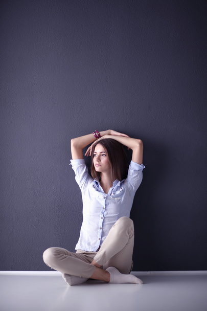 Young woman sitting on the floor near dark wall - Zdjęcie, obraz