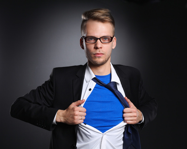 junger Geschäftsmann, der sich wie ein Superheld benimmt und sein Hemd zerreißt, isoliert auf grauem Hintergrund - Foto, Bild