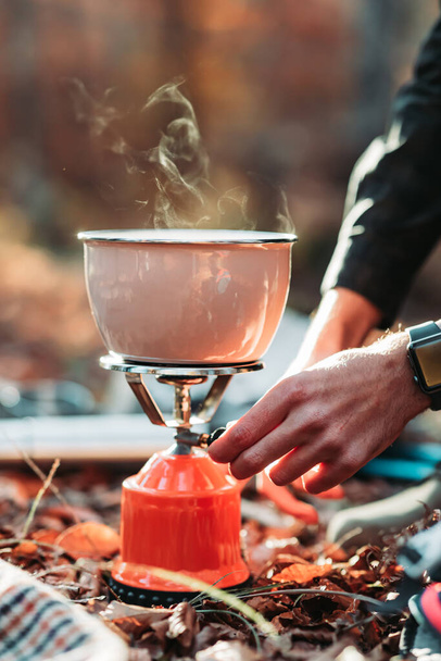 Male hand preparing soup on portable gas stove - Valokuva, kuva