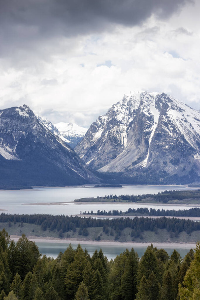 Lake surrounded by Trees and Mountains in American Landscape. Spring Season. Jackson Lake, Grand Teton National Park. Wyoming, United States. Nature Background. - Fotó, kép