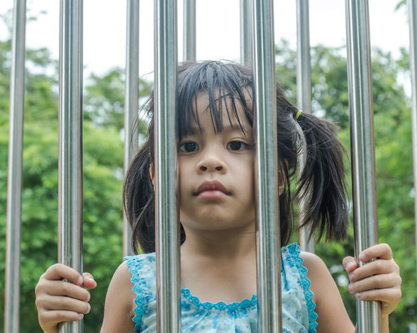 Kızlar kafeslerde, paslanmaz çelik yapılan üzgün bir yüz. - Fotoğraf, Görsel