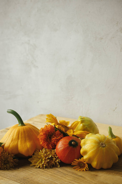 Atmospheric autumn still life. Colorful autumn flowers, pumpkins, pattypan squashes on wooden table against rustic background. Seasons greeting card, space for text. Happy Thanksgiving! - Foto, imagen