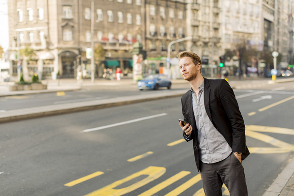 молодой человек на улице с мобильным телефоном - Фото, изображение
